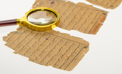 Book pages with an Arabic manuscript on a table with a light and a magnifying glass. Paleography,...