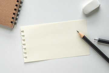 Close up. Blank Paper Sheet with Pencil, Eraser and Spiral Notebook on white Background. Empty Space for Your Text.