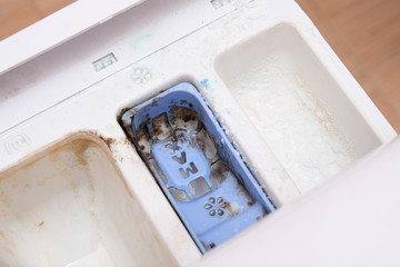 Dirty moldy washing machine detergent and fabric conditioner dispenser drawer compartment close up. Mold, rust and limescale in washing machine tray. Home appliances periodic maintenance concept