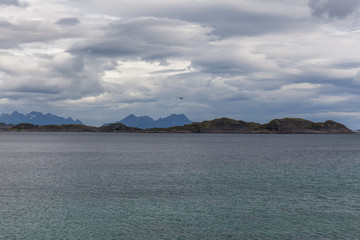 Norwegian fjord and mountains surrounded by clouds, ideal fjord reflection in clear water. selective focus.