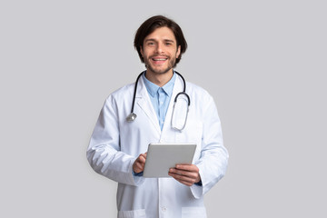 Cheerful doctor using digital tablet in hands