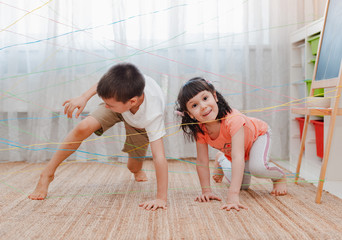 little girl boy brother, siblings, friendschild climbs through a rope web, a game obstacle quest indoors.