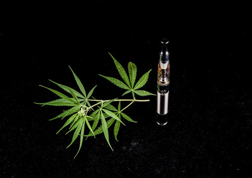 Electronic Cigarette E-cig Vaporizer - cannabis oil and cannabis leaf on black background
