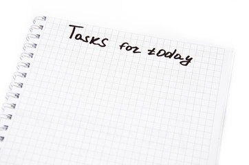 Notebook with a spiral in a cage on a white background. Top notepad contains tasks for today with a black marker, pen. Notebook top  view