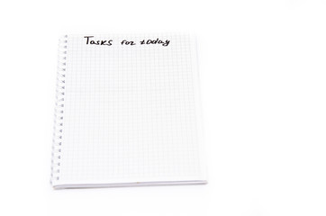 Notebook with a spiral in a cage on a white background. Top notepad contains tasks for today with a black marker, pen. Notebook top  view