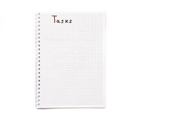 Notebook with a spiral in a cage on a white background. Above in a notebook is written tasks with a black marker, pen. Notepad top view. Notepad  Part