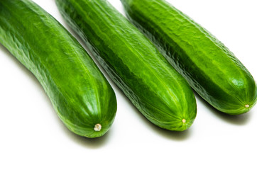 Three greenhouse green, smooth cucumbers on a white background nearby. Greenhouse cucumbers from above and in front. Cucumbers in macro, butt, tails of  cucumbers