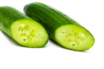 Two greenhouse green cucumbers on a white background are cut at an acute angle. Fresh cucumbers in a cut. Cucumbers in  macro