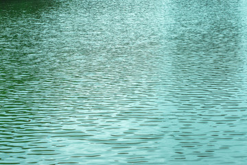 Blue texture of the surface of the water pond lake river, small waves on the water surface, light breeze. Textured ripple effect on the water. Backdrop natural background for design