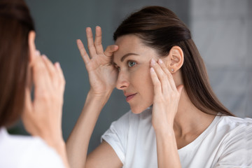 Close-up van een vrouw die in de spiegel kijkt, controleert het gezicht na de maskercrème schoonheidsbehandeling voelt tevreden, bewonder reflectie, laser huidvernieuwing, glycolzuurschil, anti-aging huidverzorgingsprocedures concept