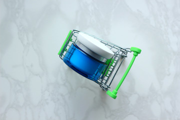 Container of moisturizing face cream on blue background. Fashion woman still life. Cosmetic theme. Beauty background with facial cosmetic products.