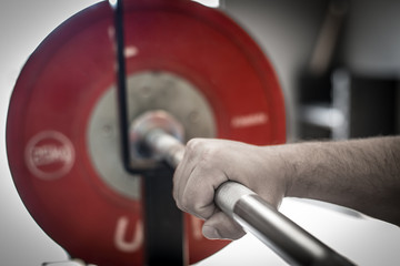 A chalked hand on a weightlifting barbell.