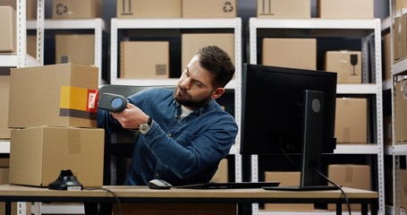 Postal office worker using computer and scanning bar code on carton box. Delivery mail service.