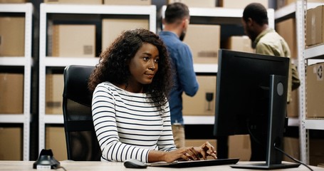 Delivery, mail service. Young people working at the post office, African American woman using computer.