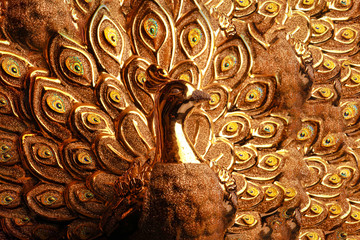 golden peacock statue isolated on dark background.
