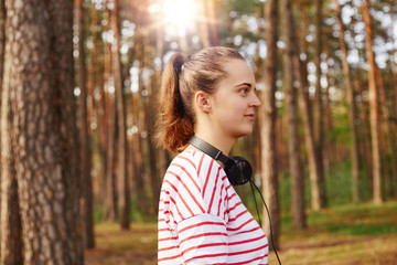 Profile of beautiful attractive young female looking ahead, having ponytail, chilling out in fresh...