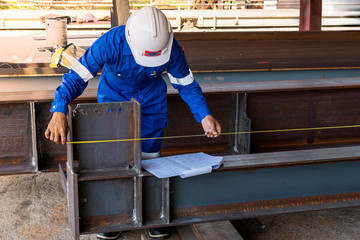 Technicians are using measuring tape to checking the accuracy of the steel structure after assembly before delivery to paint.