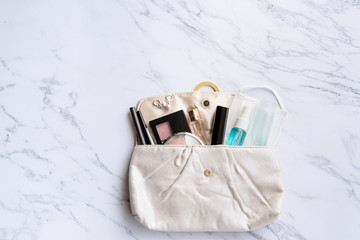 Top view of woman accessories, sanitizer, alcohol spray and protective face mask on pouch on marble background. Beauty concept. Must have item in 2020 concept. Copy space, flat lay