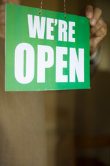 Business owner hanging an open sign at a glass door