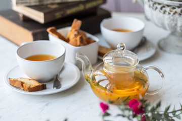 Obraz na płótnie Canvas Sea-buckthorn tea in a glass teapot with white mugs on a light background. selective focus.