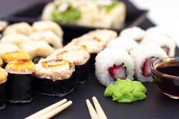 Set of rolls, wasabi, sauce and wooden sticks on a stone black table.