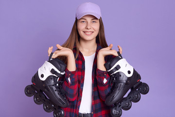 Studio shot of happy Caucasian woman with long beautiful hair holding skating roller in hands,...