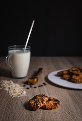 Oat chocolate cookies close up with a cup of milk, rolled oats and chocolate cookies
