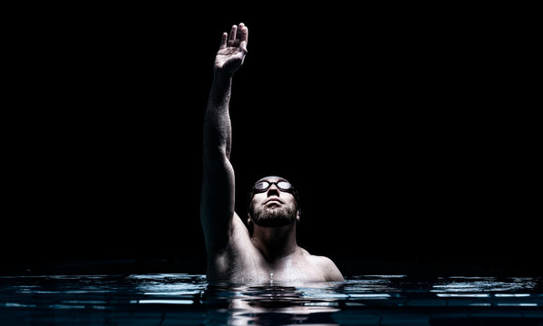 Swimmer in the pool raises his hands up. Water Sports Victory Concept.