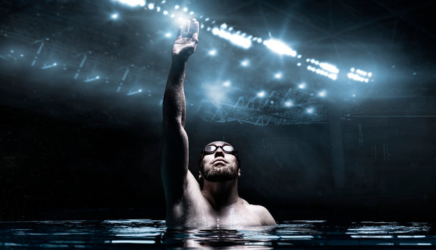 Swimmer in the pool raises his hands up. Water Sports Victory Concept. Arena with flashes.