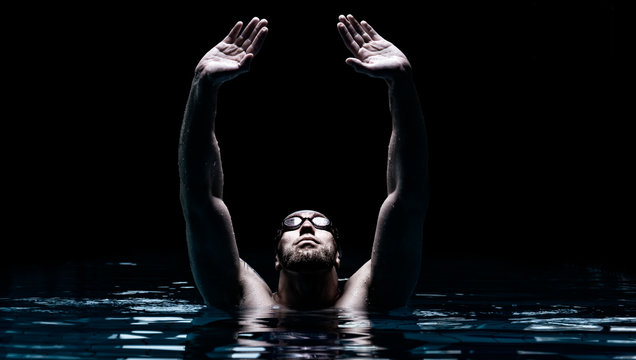 Swimmer in the pool raises his hands up. Water Sports Victory Concept.