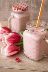 Pink raspberry cream smoothie in mason jar and tulips