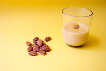 almond dessert in glass with fresh almonds on yellow background. Concept of dieting, healthy eating, homemade food. Free copy space.