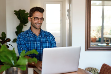 Smiling man working from home with a laptop