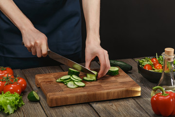 Woman cooking fresh healthy salad. Female hands cutting vegetables on board on wooden table with copyspace.