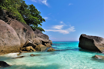 Thailand. Sunny day. Amazing Andaman Sea, clear aquamarine water. Large picturesque boulders and trees on the shore. Bright blue sky. Paradise.