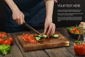 Woman cooking fresh healthy salad. Female hands cutting vegetables on board on wooden table with sample text.