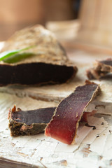 Sliced venison steak, dry meat of wild roe on wooden board, vertical image