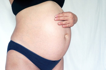 tummy of a pregnant girl at 9 months of pregnancy