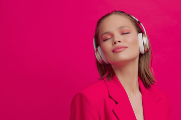 A beautiful young girl in wireless headphones listens to song with a good mood. bright colorful music poster.