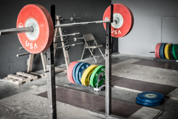 Weight plates on a barbell over an olympic platform.