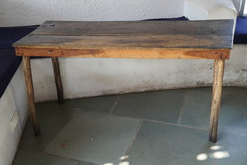 Dark Ugly old damaged wooden table kept outside a house in a village. A seating area is visible in the background.