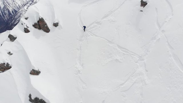 Aerial view of a backcountry skier rides freeride on a steep slope. Professional ski extreme in the mountains of the Alps or the North Caucasus