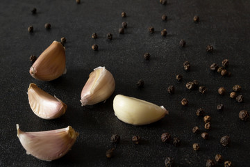 garlic cloves with pepper on a black background