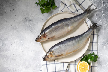 Herring on a white plate on a light gray table. Salted fish	