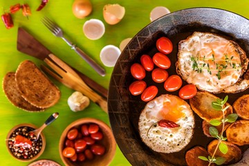 Fried eggs in a frying pan with cherry tomatoes and bread for breakfast . Fried potatoes and tomatoes. Diet food. Rural breakfast with fresh eggs.
