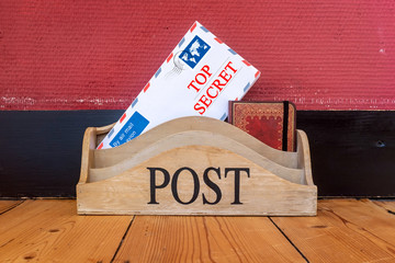 The words Top Secret printed on an envelope in a wooden letter holder.