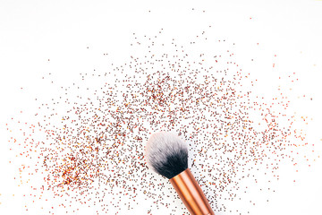 Makeup brush and golden sparkles on white background,