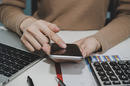 cropped shot businesswoman hand using digital mobile phone calculating with document report on desk in meeting room at office, digital marketing, work from home, business finance, technology concept