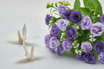 White origami crane and purple flowers, shallow depth of field