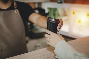 young happy handsome man barista serving hot coffee cup to friendly female customer over counter in modern cafe coffee shop, cafe restaurant, service mind, small business owner food and drink concept
